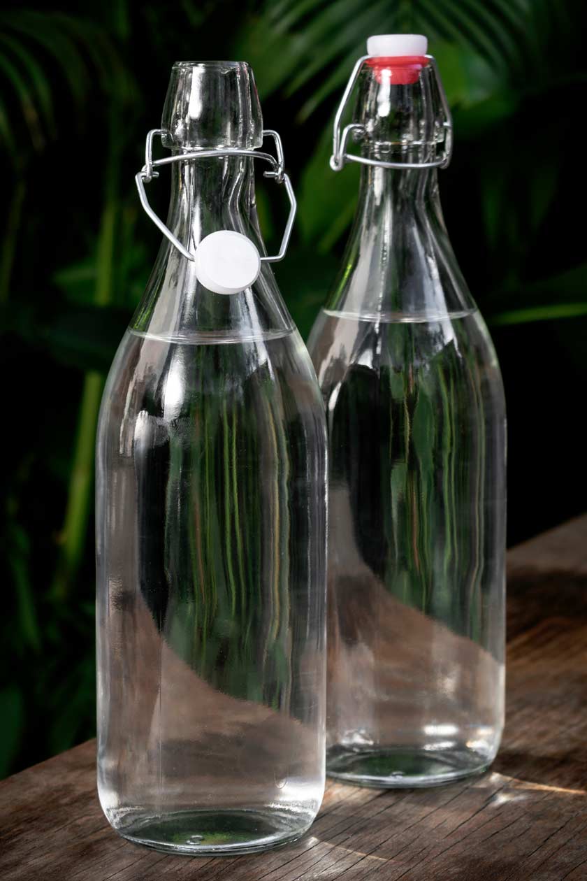 Zwei Bügelflaschen aus Glas stehen nebeneinander auf einem Tisch